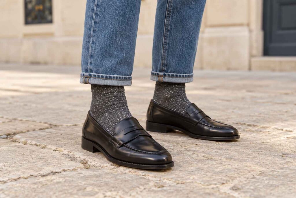 Chaussettes à paillettes grises portées avec un jean retroussé et des mocassins noirs